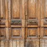 Per farlo varchiamo un portone in legno che presenta dei fasci littori vicino alle maniglie: ricordano come lo stabile fu costruito durante il Ventennio